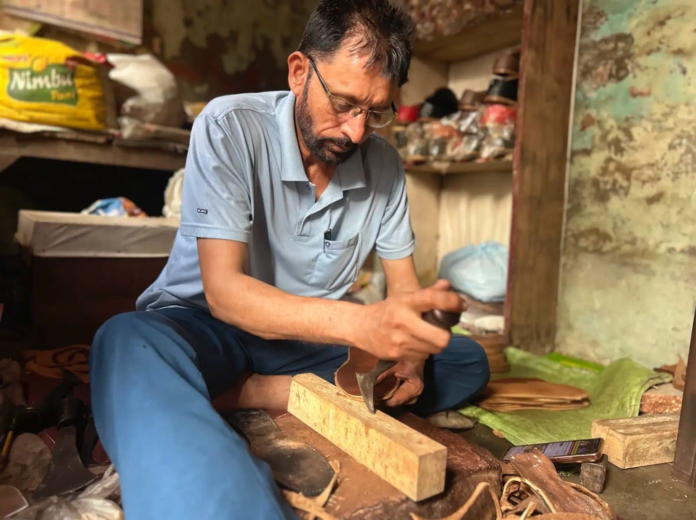 A traditional leather dalit artisan Mahendra crafting handmade leather juttis in Kandela village, Jind district, Haryana.